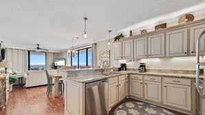 A modern kitchen with a dishwasher, granite countertops, and light-colored cabinetry.