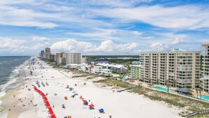 A beach resort with a long sandy beach, multiple hotel buildings, and a clear view of the ocean.