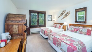 A room with two beds, a wooden cabinet, a table with a coffee maker, and a window with a view of greenery. - Manitou Lodge 3 Hotel Room by Alpine Lodging Telluride (Telluride)