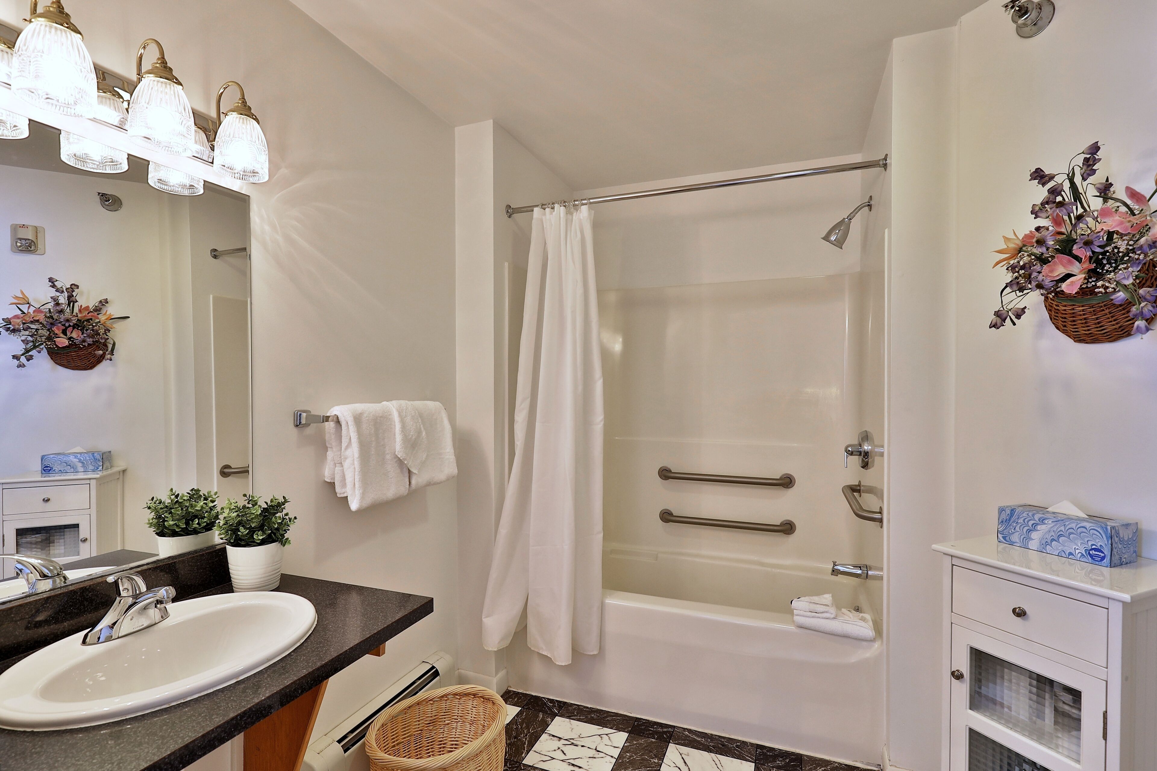 A bathroom with a sink, mirror, shower, and towel rack.