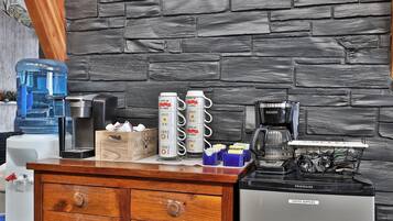 A kitchenette with a coffee maker, water dispenser, and storage containers.