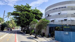 Uma rua com um edifício de fachada curva, entrada com portão e céu claro.