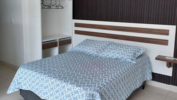 Un dormitorio con cama, armario y estante en la pared.