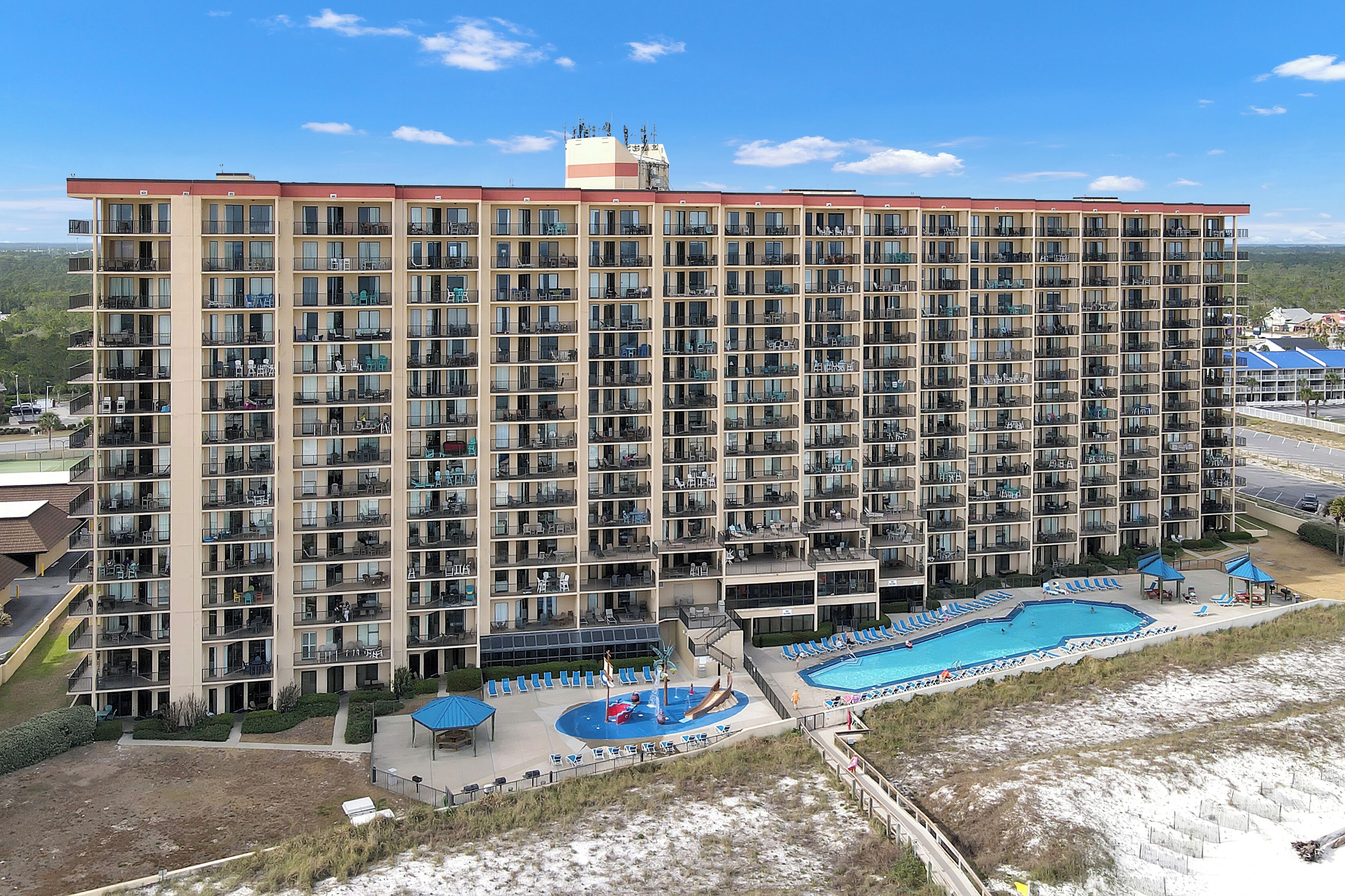 A large multi-story hotel with a swimming pool and outdoor seating area.