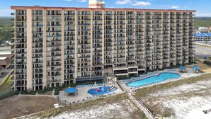 Un grand hôtel à plusieurs étages, doté d’une piscine et d’un espace extérieur aménagé avec des sièges.