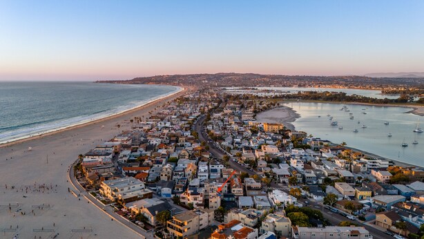 Un pueblo costero con playa, puerto deportivo y edificios residenciales muy cercanos.