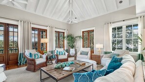 A spacious living room with a high ceiling, large windows, and a mix of wicker and upholstered furniture. - Sieber Cottage | Next to Coquina Pool, Free Tennis & Fitness (Rosemary Beach)