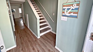 Una scala con corrimano che porta a un pianerottolo, pavimento in legno e un muro con un elemento decorativo a parete.