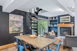 Ein modernes Interieur mit Essbereich, Wendeltreppe, Kamin und Kunstwerken an den Wänden.