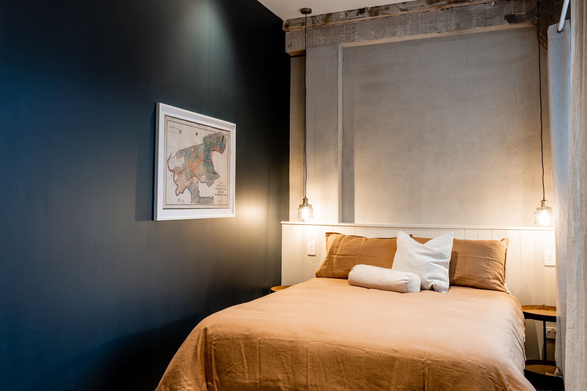 Quarto com uma cama, um mapa na parede e duas luminárias de cabeceira.