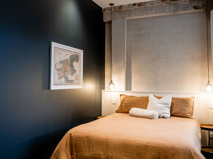 Quarto com uma cama, um mapa na parede e duas luminárias de cabeceira.