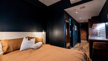 A modern hotel room with a large bed, a desk, and a bathroom visible through an open door.