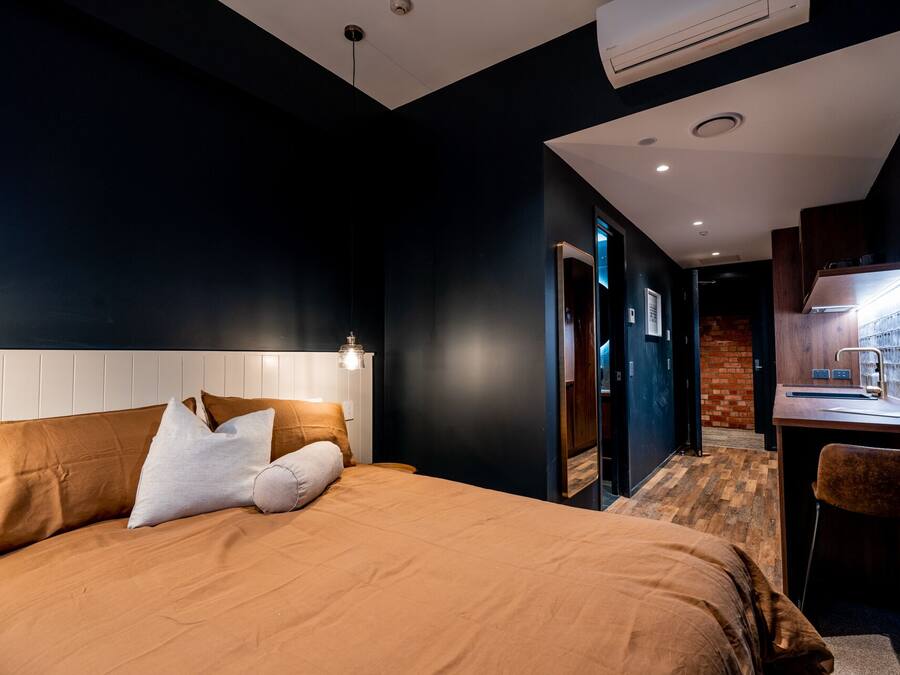 A modern hotel room with a large bed, a desk, and a bathroom visible through an open door.