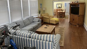Una sala de estar con un sofá a rayas, una mesa de centro de madera y un televisor sobre un mueble de madera.