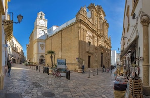 A cobblestone street with historic buildings, a clock tower, and a market stall.