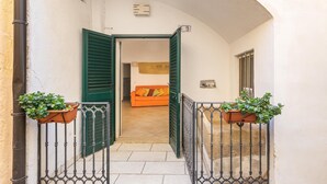 A narrow corridor with a tiled floor leading to an open room with a sofa and a window. - 3180 Appartamento Raffaella by Barbarhouse (Gallipoli)