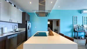 Une cuisine moderne dotée d’un îlot central, d’appareils électroménagers en acier inoxydable et d’un mur d’accent bleu.