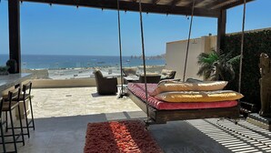Une terrasse au bord de la plage, dotée d’un lit suspendu, d’un coin salon et offrant une vue sur l’océan.