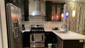 Una cocina compacta con refrigerador, estufa, horno y pileta.