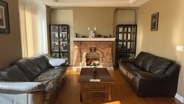 Una sala de estar con dos sofás de cuero, una mesa de centro de madera, una chimenea de ladrillo y objetos decorativos en la repisa.