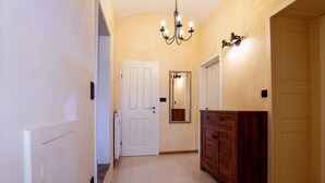 A hallway with a wooden cabinet, a white door, and a chandelier.