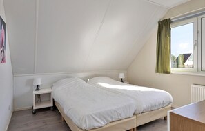 A bedroom with a bed, bedside tables, a window with curtains, and a radiator. - 3 bedroom cozy home in Vlagtwedde (Vlagtwedde)