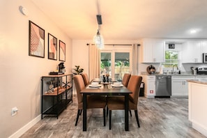 A modern kitchen with white cabinets, a stainless steel dishwasher, and a coffee bar. - Modern Pool Home Near UF, Downtown, & Devil's Millhopper Geological State Park (Gainesville)