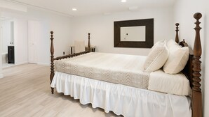 A bedroom with a wooden four-poster bed, a mirror on the wall, and a door leading to another room. - "Stay in Style Downtown Grandville - Discounts for Nurses!" (Grandville)