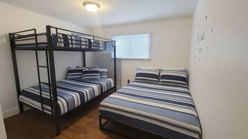 A room with two bunk beds, a window with blinds, and a wall with star decorations.