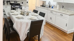 A modern kitchen with white cabinetry, a dining table set for four, and a stove. - "Stay in Style Downtown Grandville - Discounts for Nurses!" (Grandville)