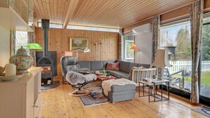 Un salon chaleureux avec une cheminée, des murs en bois, un canapé et une table à manger.
