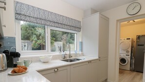 Une cuisine moderne dotée d’une grande fenêtre, d’un évier et d’un lave-linge encastré.