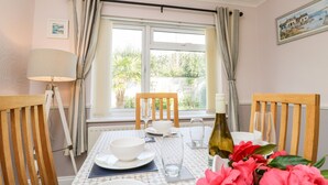 A dining area with a table set for two, a bottle of wine, and a vase of flowers.