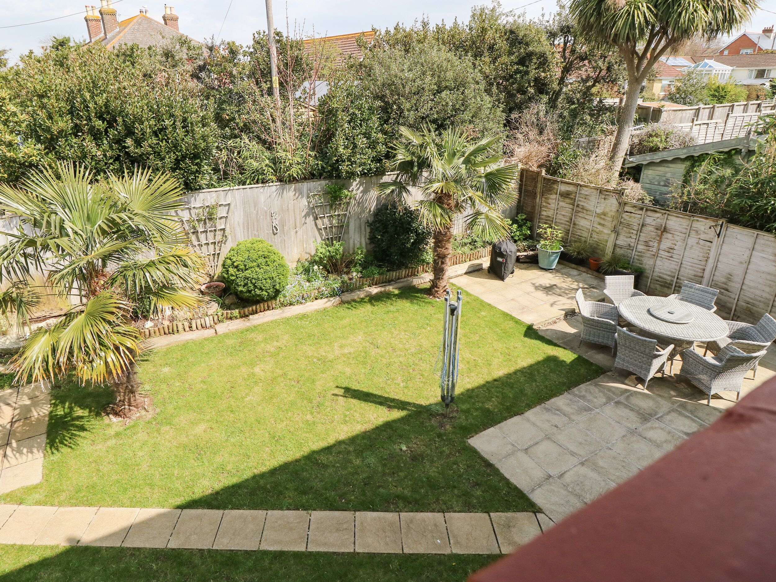 A backyard with a lawn, a patio table with chairs, and various plants.