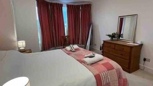 A bedroom with a bed, a dresser, a mirror, and a lamp. - Stunning 4-bed Apartment in Cambridge (Cambridge)