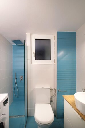 A bathroom with a toilet, a shower, and a sink.
