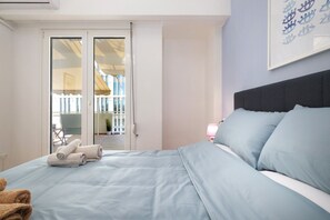 Een hotelkamer met een bed, nachtkastje, lamp en uitzicht op het balkon.