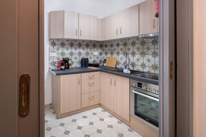Compact kitchen with oven, microwave, and geometric tile backsplash and floor.