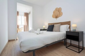 A modern bedroom with a large bed, two bedside tables, a wall-mounted light fixture, and a view of the outdoors. - 11CRC1037 Newly decorated Flat near Sants Station (Barcelona)