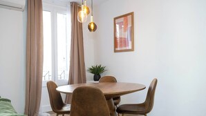 Un coin repas avec une table ronde en bois, quatre chaises marron et une plante en pot.