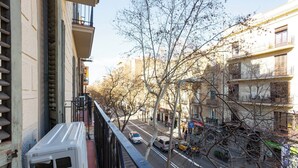 Une vue sur la rue depuis un balcon, avec des bâtiments, des arbres et des véhicules.