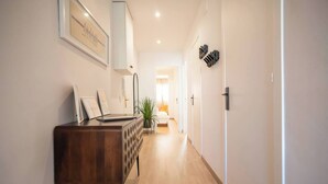 A hallway with a wooden desk, framed pictures, and a potted plant. - 12CRC1038 - Refurbished Big & Cozy Apartment (Barcelona)