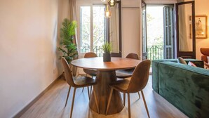 A dining area with a round table, chairs, and hanging pendant lights. There is a potted plant and a green sofa in the background. - 12CRC1038 - Refurbished Big & Cozy Apartment (Barcelona)