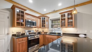 Una cocina con armarios de madera, una estufa de acero inoxidable y una encimera de granito negro.