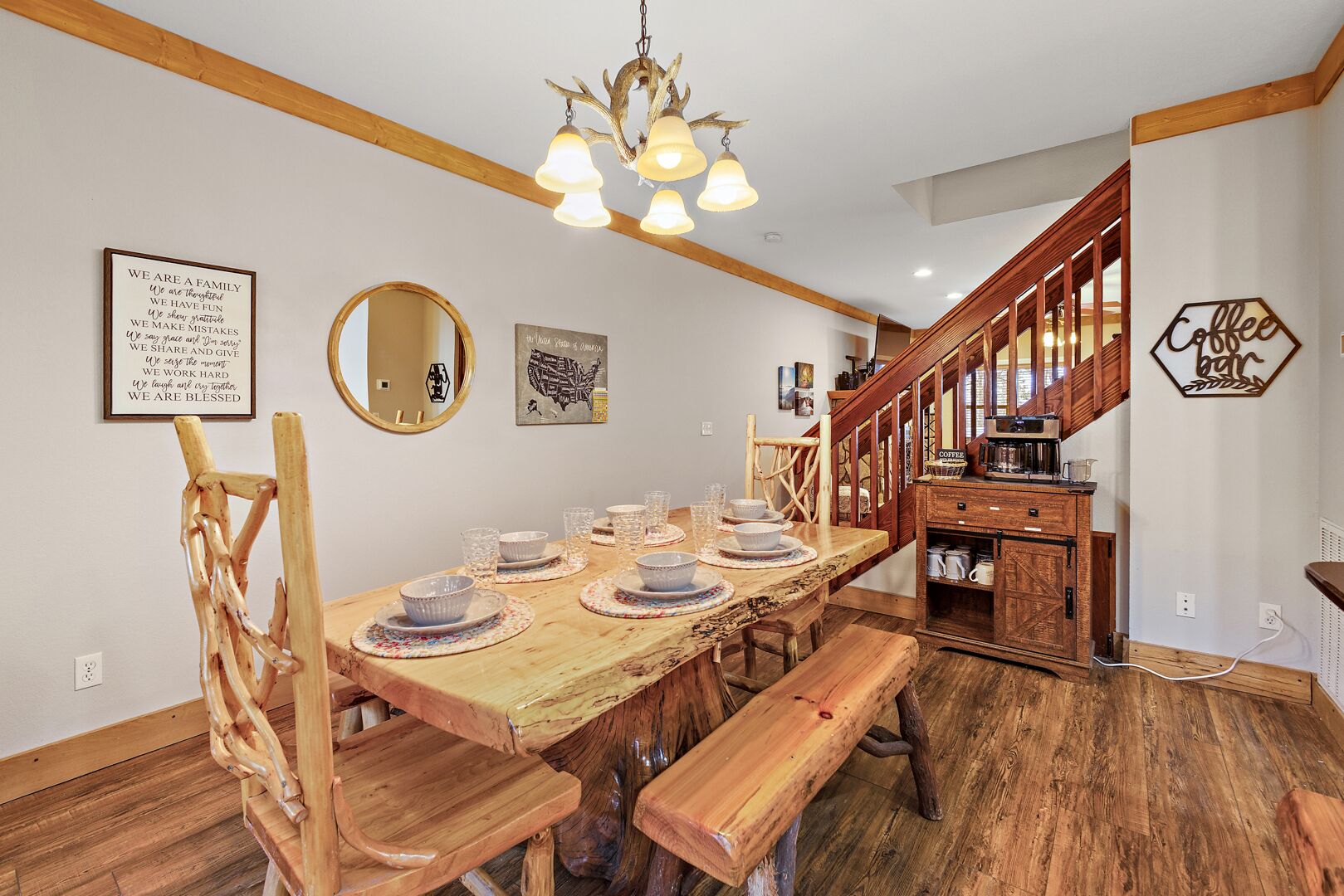 A dining area with a wooden table set for six, a wooden bench, and a coffee station.