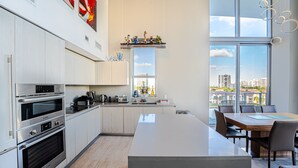 A modern kitchen with built-in appliances, a large island, and a dining area with a view of the city.