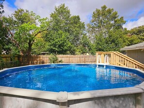 Ein Schwimmbad mit Holzterrasse und Holzzaun im Hintergrund.