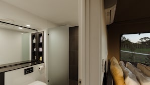 Ein modernes Badezimmer mit Toilette, Spiegel und Duschbereich.
