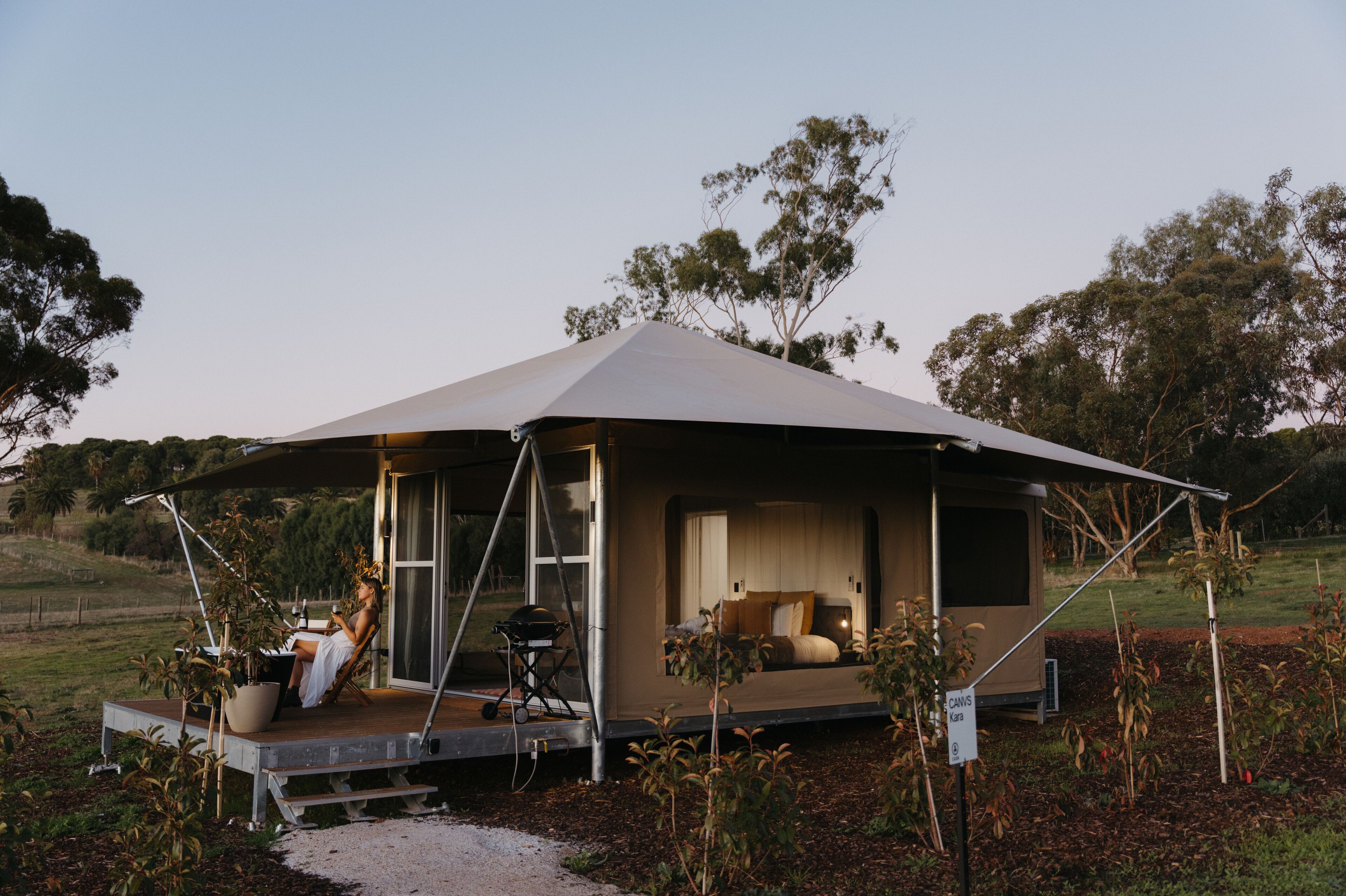 A modern, open-air tent-style accommodation with a spacious interior, a balcony, and a view of the surrounding landscape.