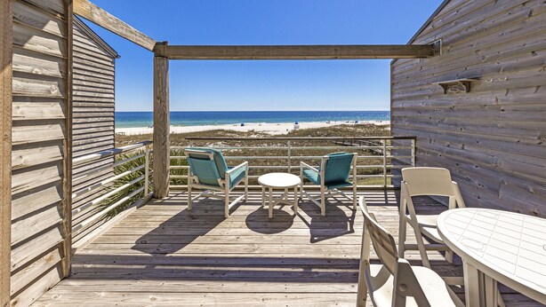 A wooden deck with a table and chairs, overlooking a beach. - Needle Rush Point D33 | Walk to FloraBama | 2 Pools | Boat Slips | My Beach Getaways (Pensacola)